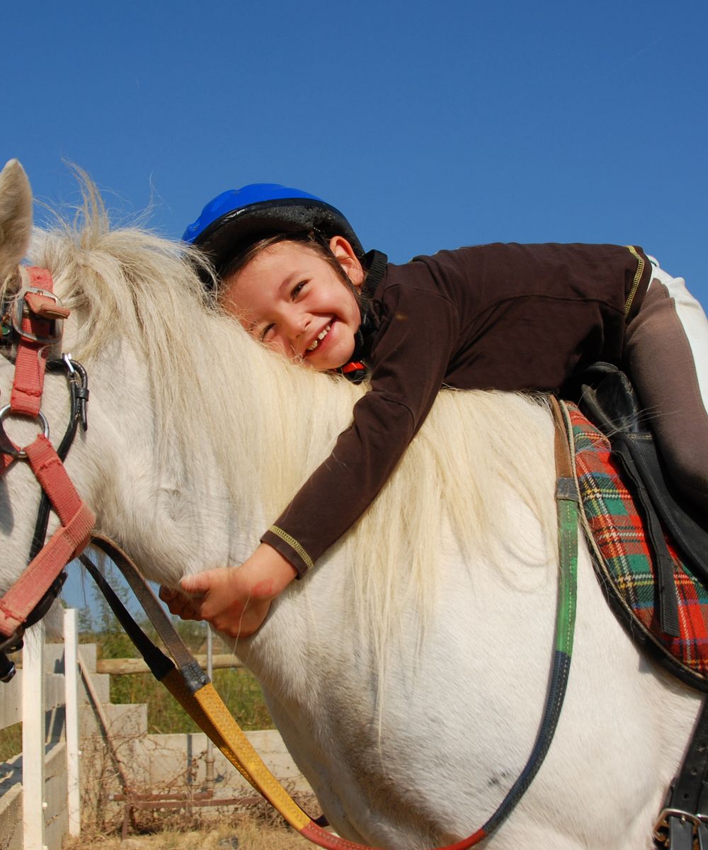 Un enfant allongé sur un poney à la ferme